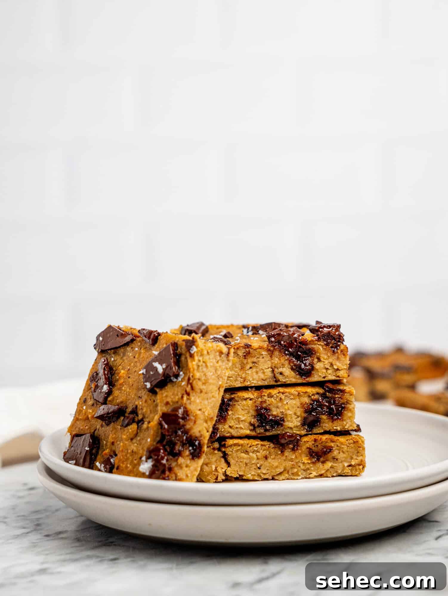Gooey Chickpea Cookie Bars 2 Healthy cookie bars with dark chocolate stacked on a white plate.