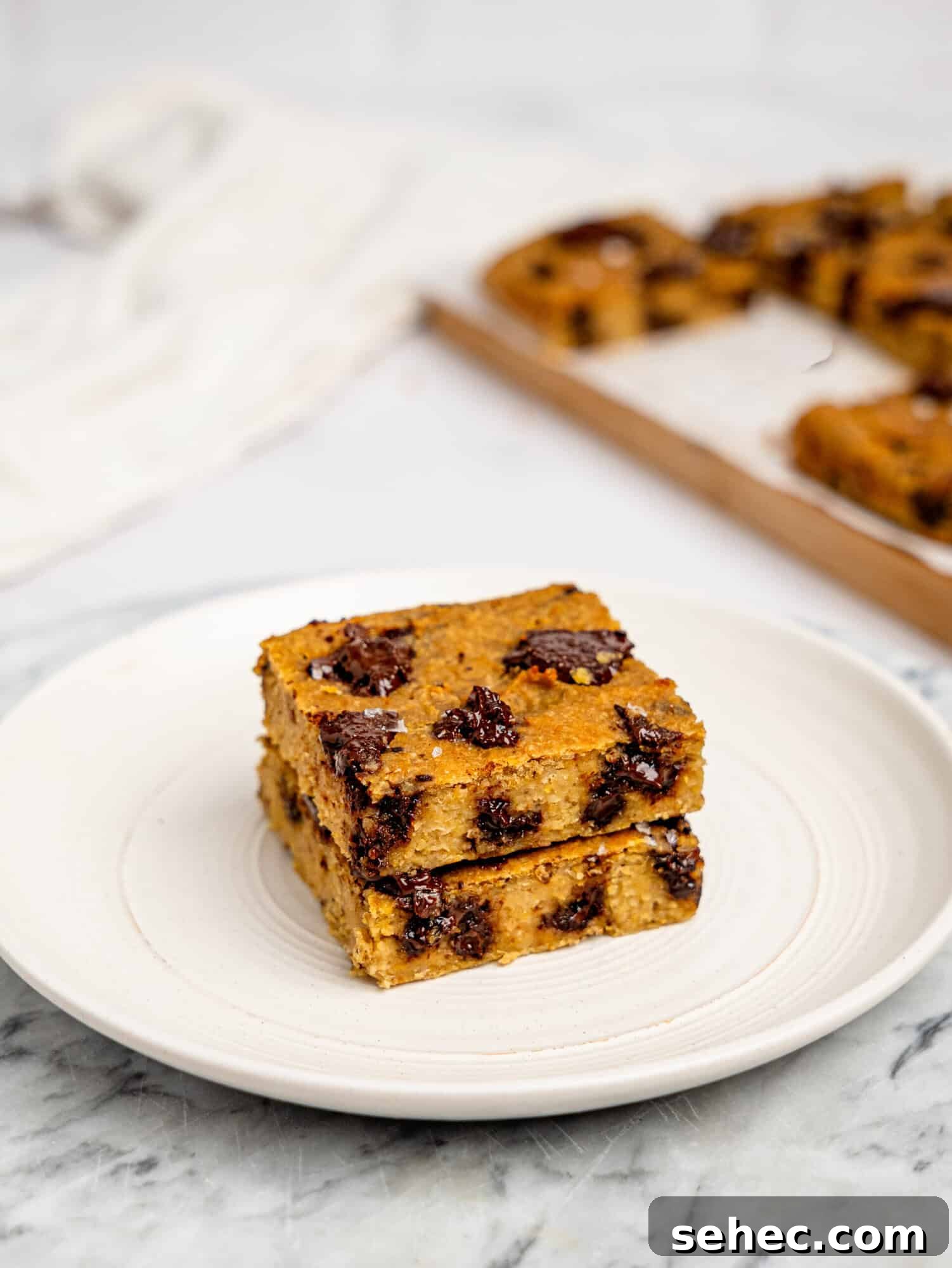 Gooey Chickpea Cookie Bars 5 Two chickpea cookie bars stacked on top of each other on a white plate.