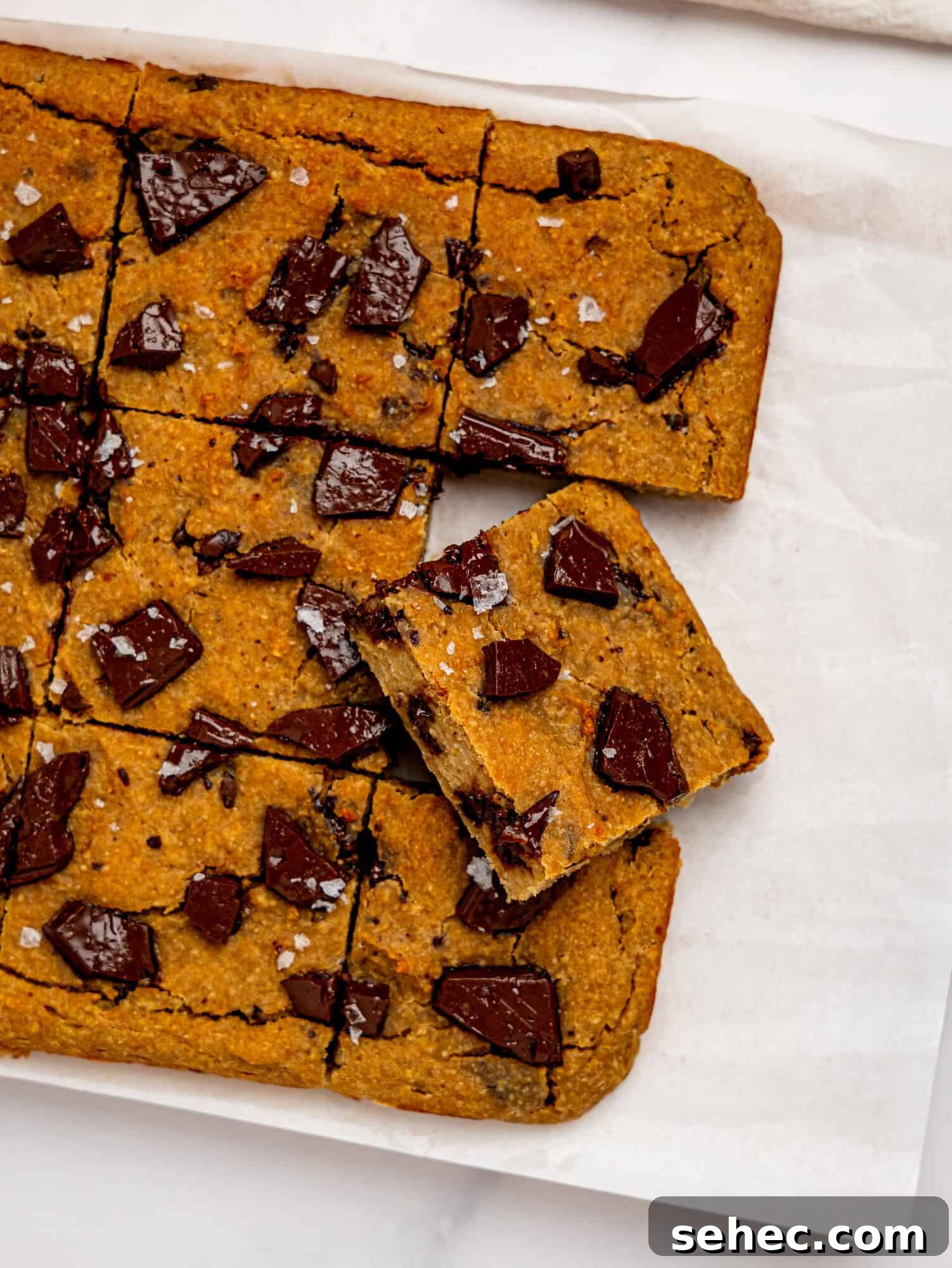 Gooey Chickpea Cookie Bars 9 Bird's eye view of chickpea cookie bars on a sheet of white parchment paper.