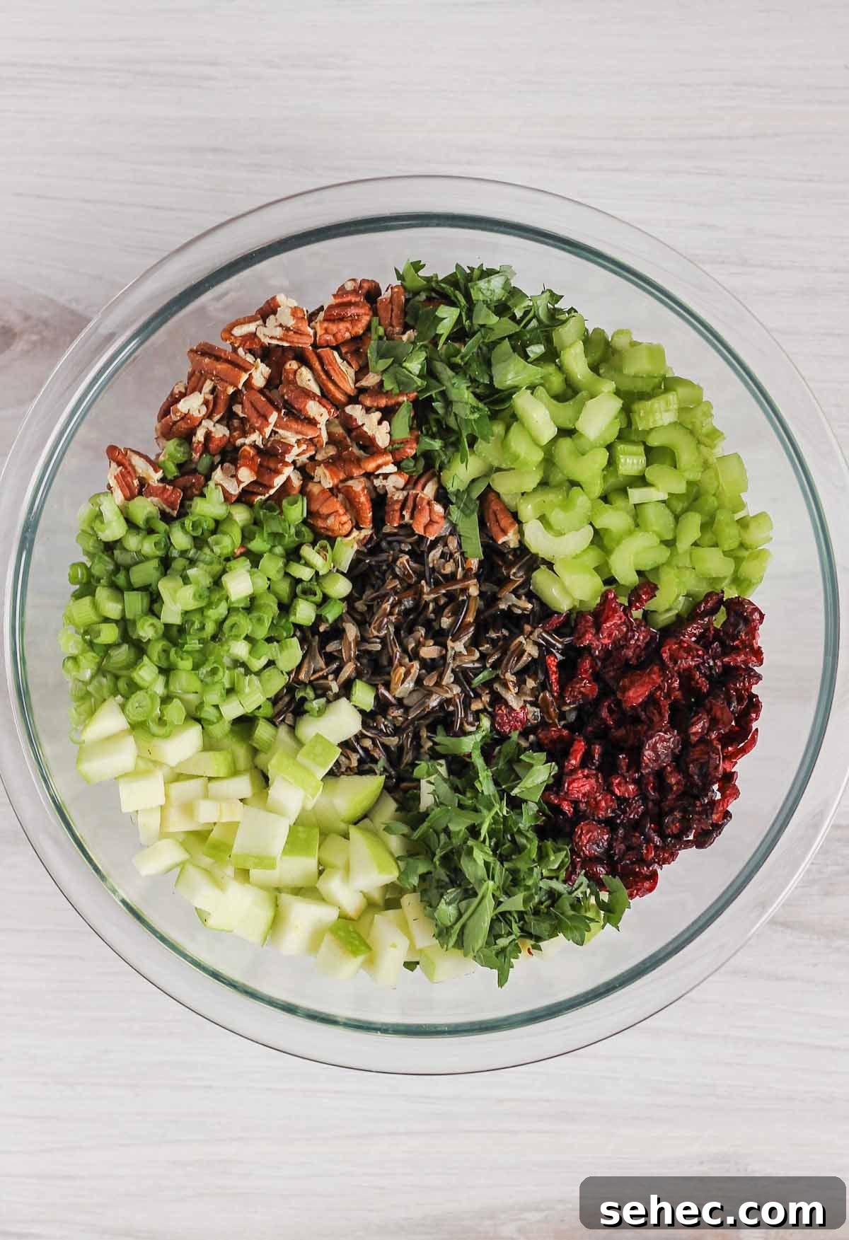 Cold Wild Rice Salad with Cranberries and Pecans 8 Wild rice salad ingredients in glass mixing bowl before being mixed together.