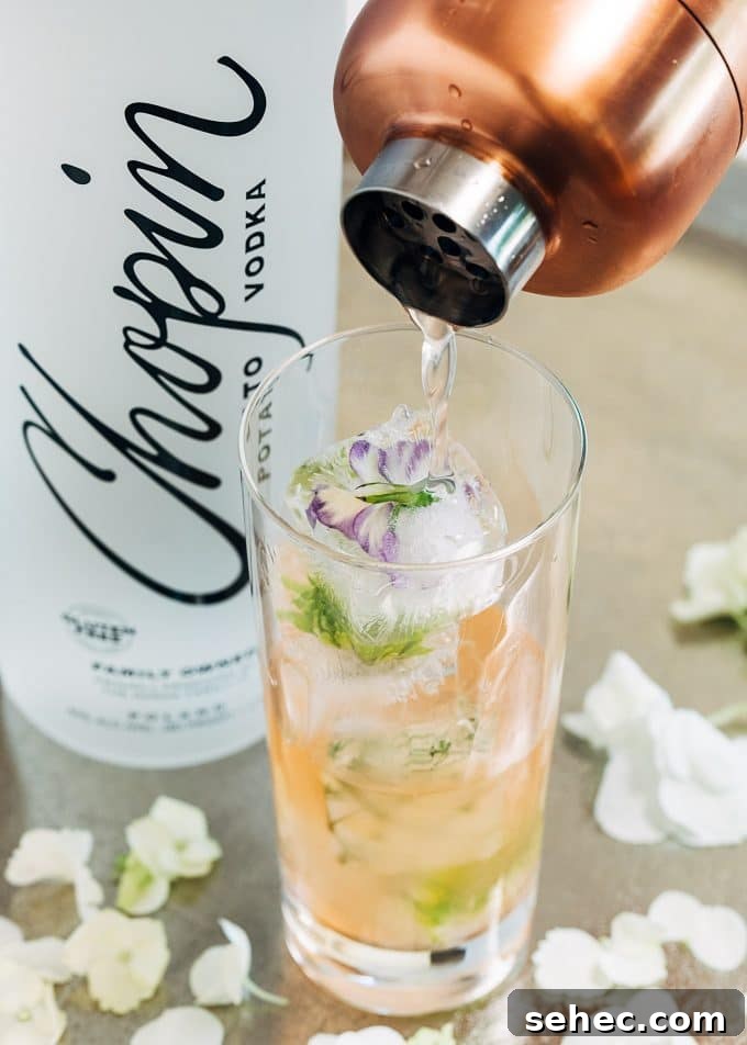 Chopin Spring Equinox Vodka Cocktail Recipe 6 pouring vodka cocktail into a glass with flower ice cubes