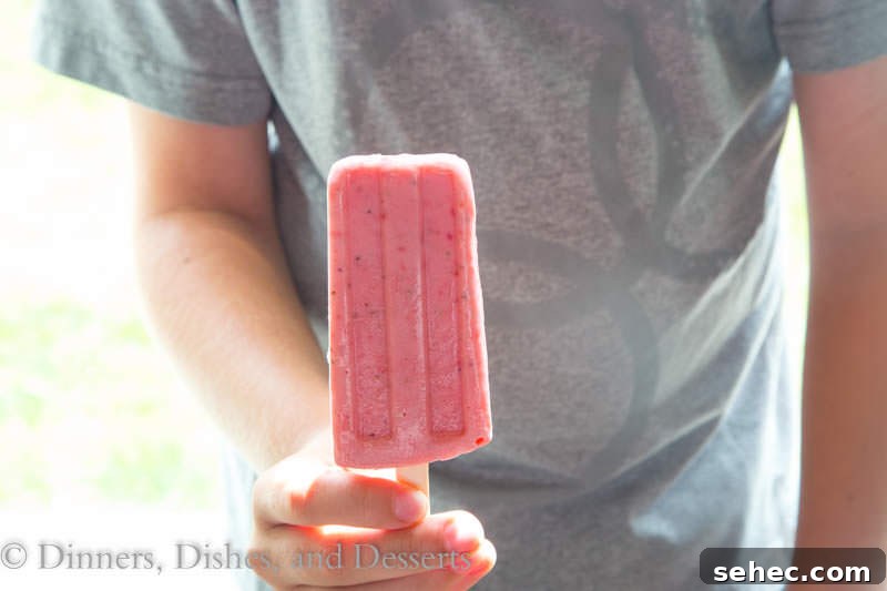 Strawberry Greek Yogurt Popsicles Recipe 3 strawberry greek yogurt popsicles in a hand