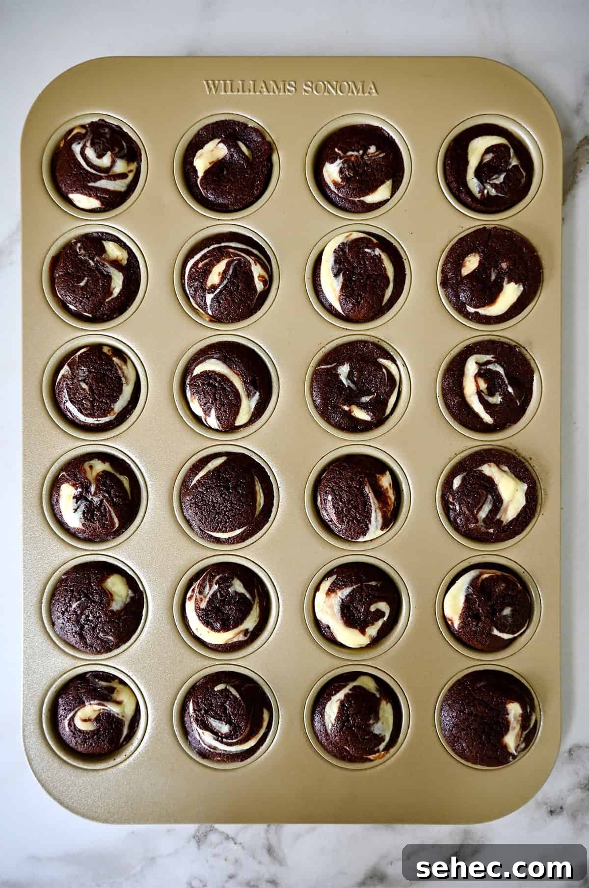 Baked cheesecake brownie bites are in a mini muffin pan.