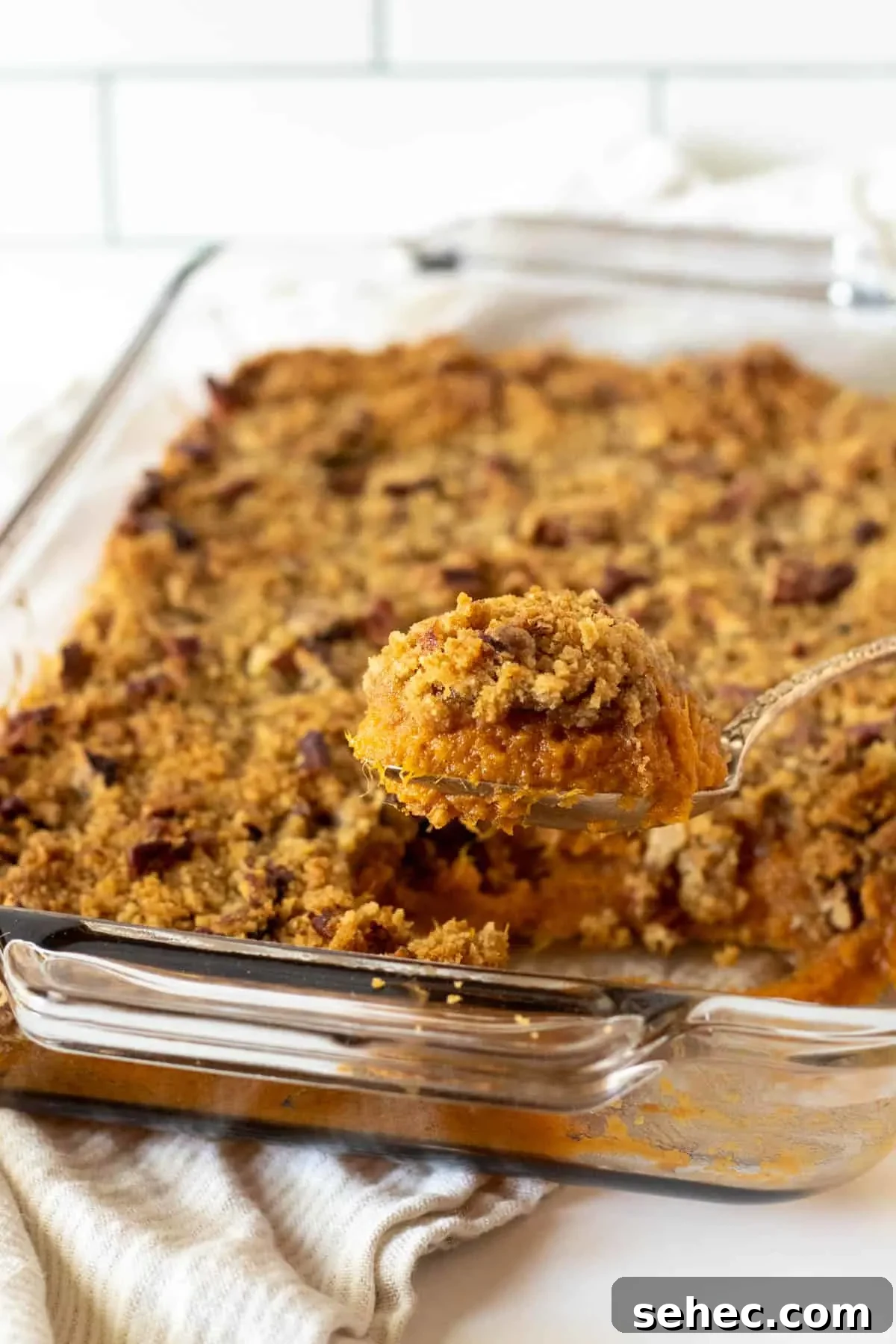 Classic Sweet Potato Casserole with Pecan Topping 8 Baked sweet potato casserole with a spoonful being served from the baking dish.