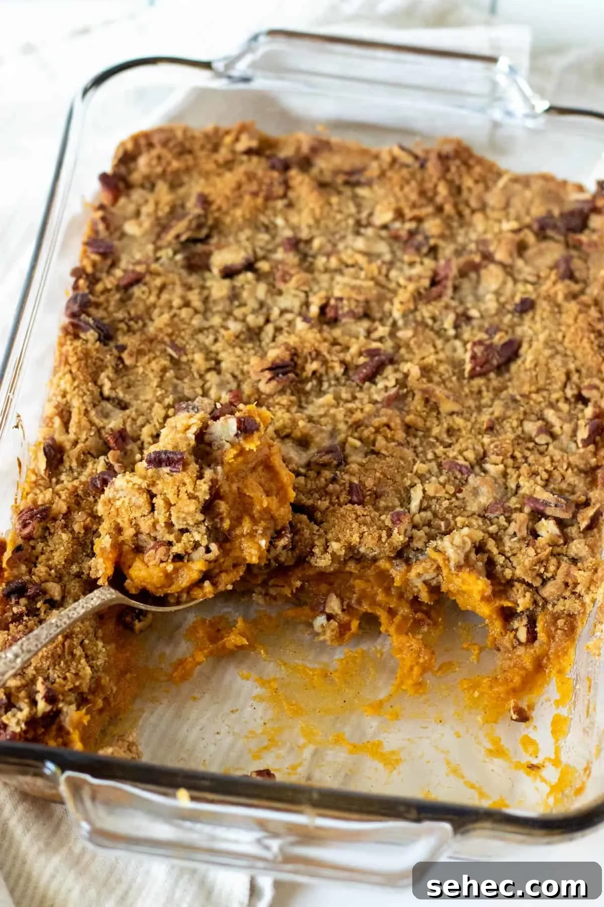 Classic Sweet Potato Casserole with Pecan Topping 9 Sweet potato casserole served from a dish with a spoon.