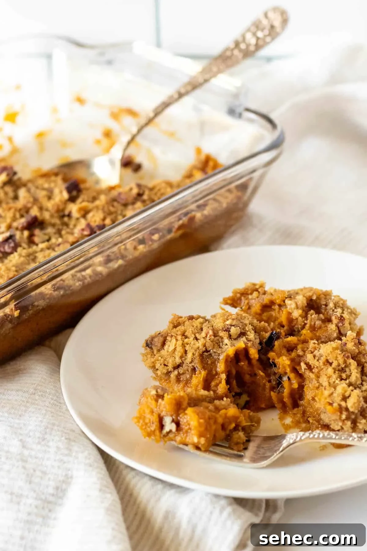 Classic Sweet Potato Casserole with Pecan Topping 3 White plate with a serving of sweet potato casserole.