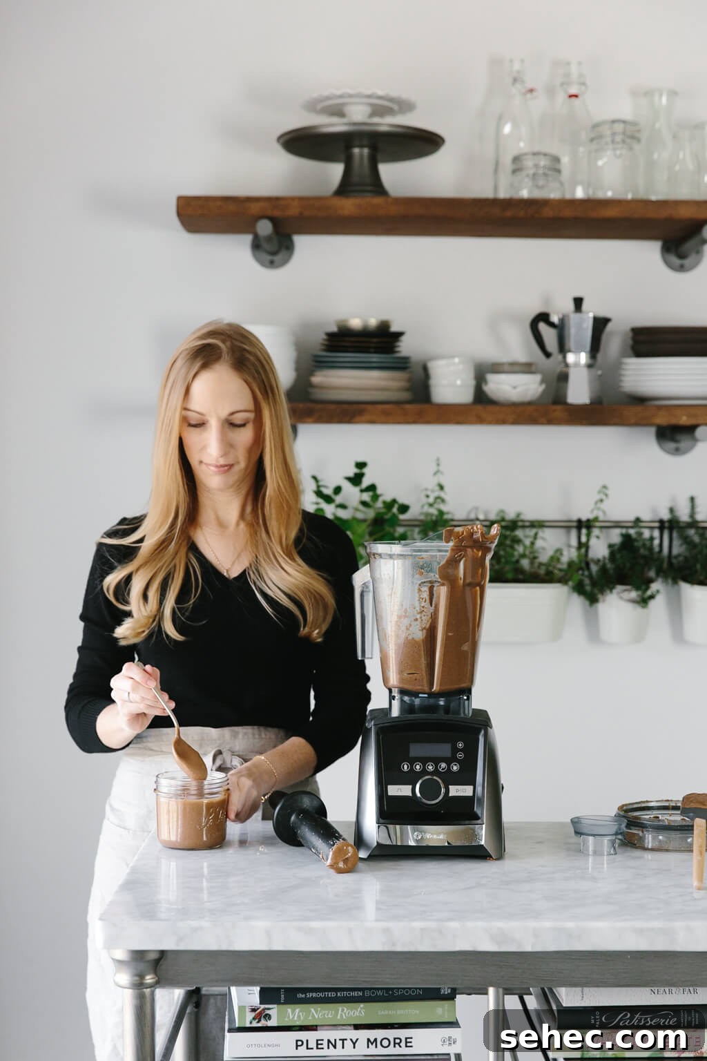 How to Make Almond Butter in 1 Minute 5 Girl standing next to Vitamix blender with almond butter in it.