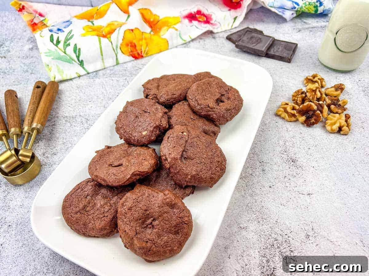 17 Buttery Fall Cookie Recipes for Cozy Shorter Days 13 A plate of chocolate cookies with walnuts and chocolate pieces on the side.