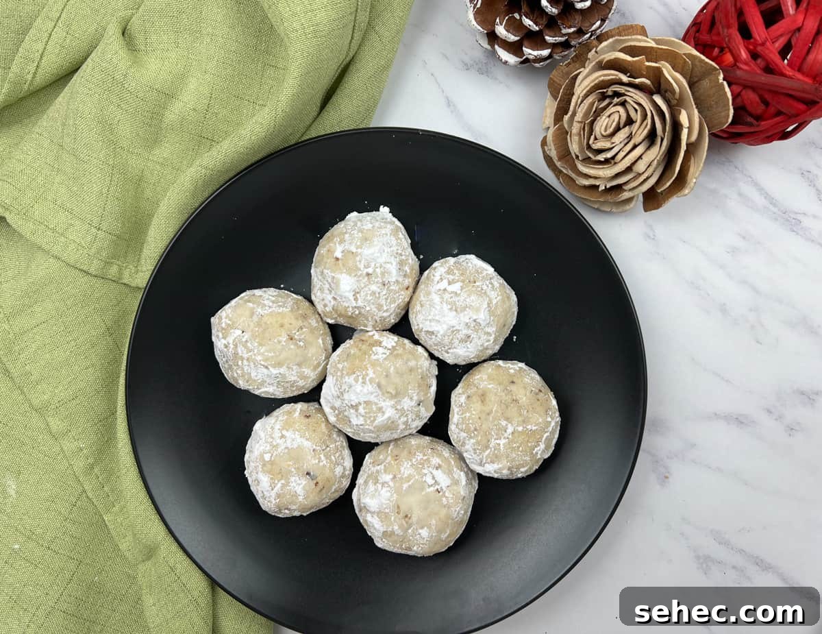 17 Buttery Fall Cookie Recipes for Cozy Shorter Days 14 Top-down shot of seven pecan butter balls on a black plate.