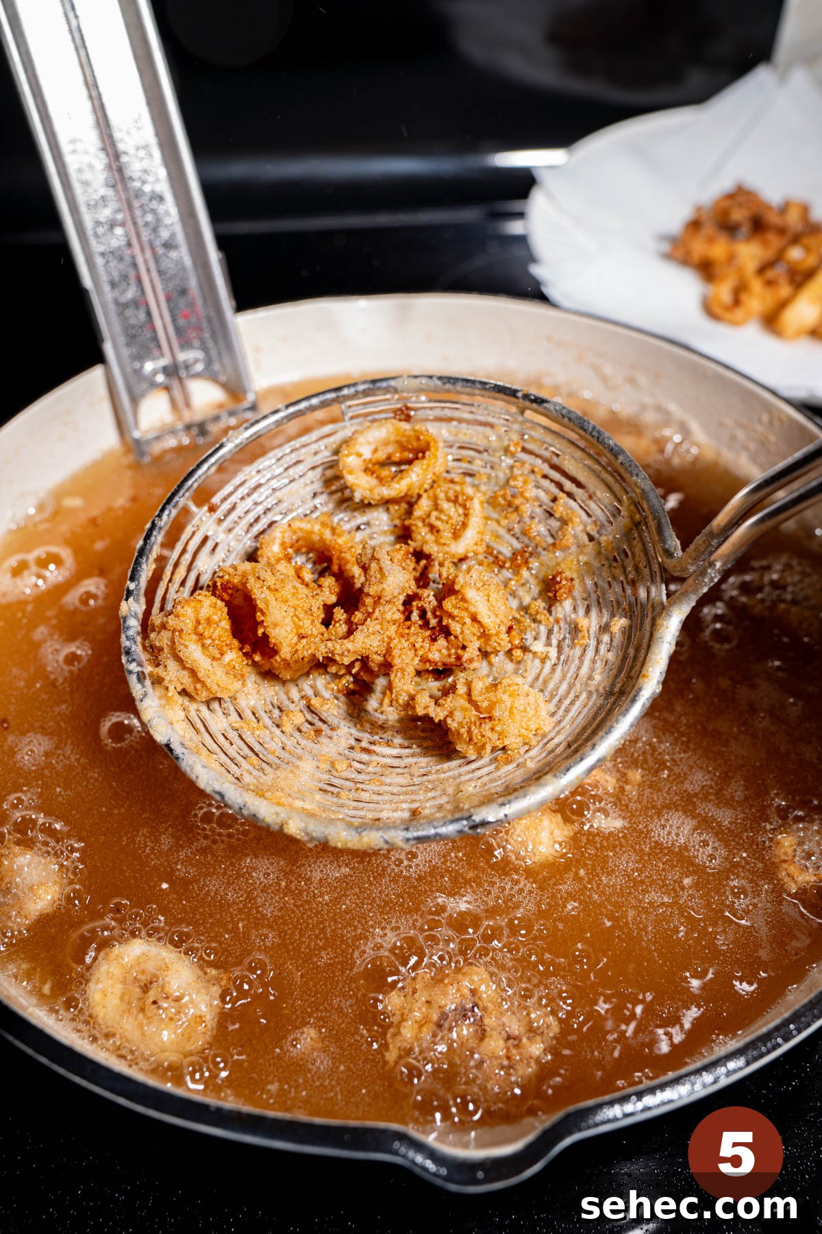 Crispy Fried Calamari with Tender Squid Rings 5 A strainer scoops the fried calamari from the hot oil after frying.
