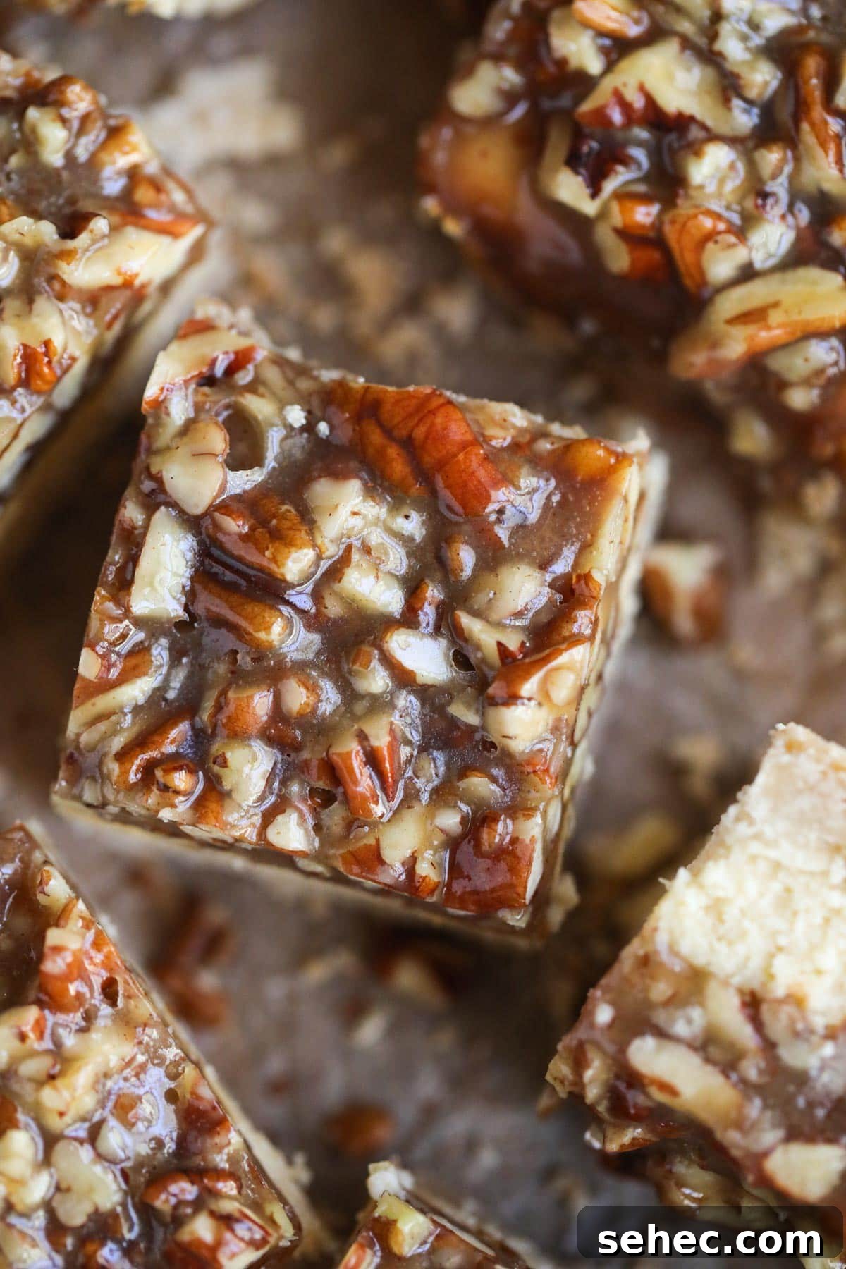 Pecan Pie Cheesecake Bars Recipe 11 pecan pie cheesecake bars on parchment paper.