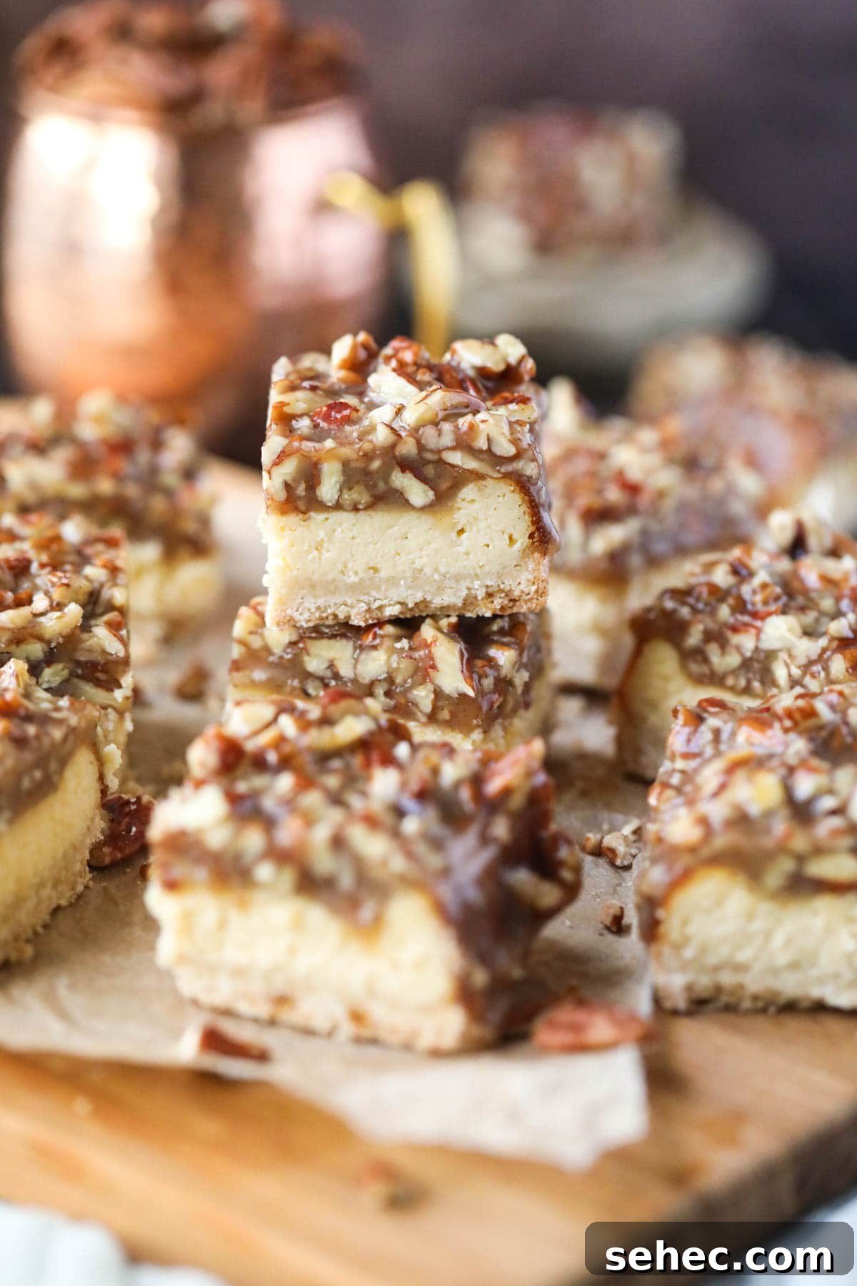 Pecan Pie Cheesecake Bars Recipe 10 pecan pie cheesecake bars on parchment paper.