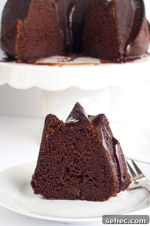 Chocolate Whiskey Cake Recipe 5 slice of Chocolate Whiskey Cake on a plate with the rest of the whiskey bundt cake on a cake plate behind it