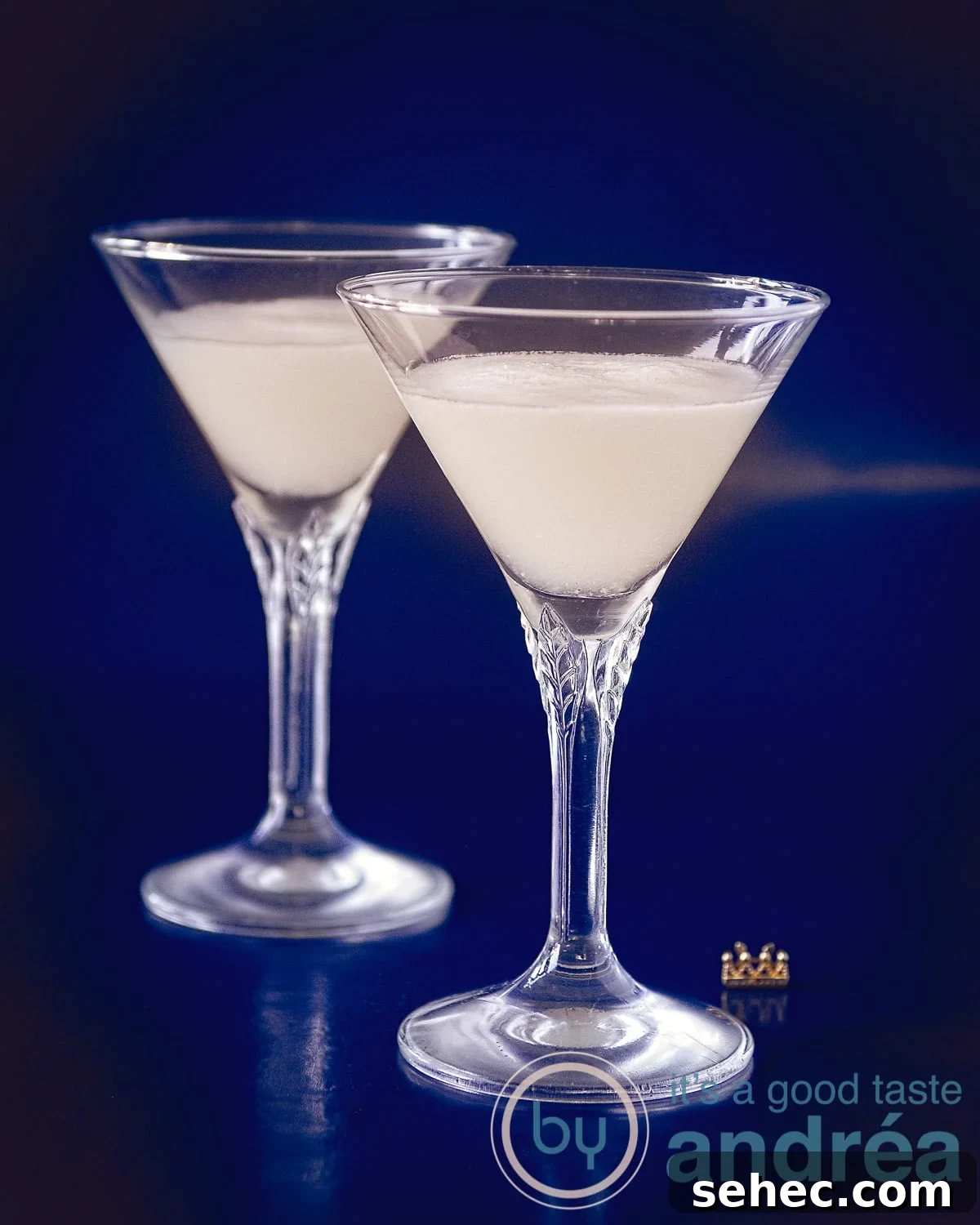 Sherry Sour Cocktail Recipe 2 Two crystal glasses filled with sour sherry cream on a blue background.