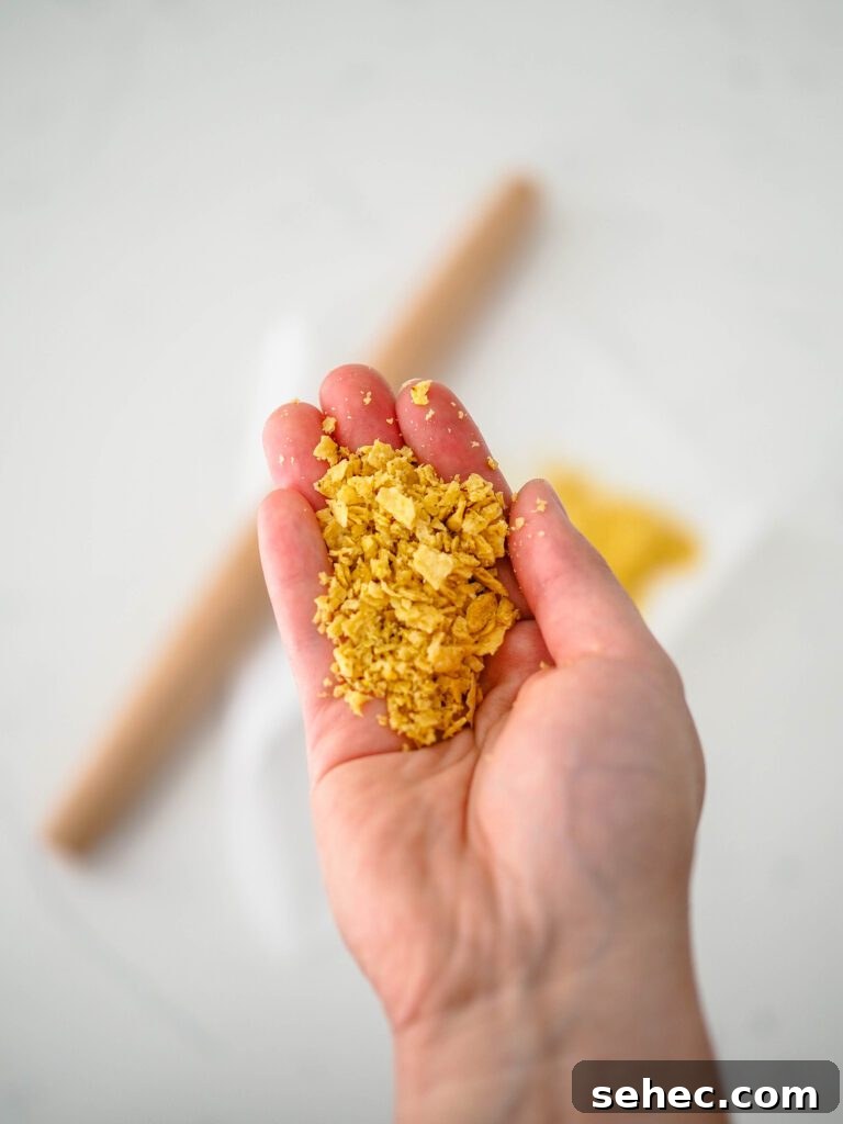 Cajun Tortilla Chip Crusted Tilapia Recipe 5 A hand holds tortilla chip crumbs.