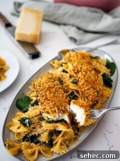 Cajun Tortilla Chip Crusted Tilapia Recipe 8 Two breaded tilapia filets on top of a pile of Cajun pasta and spinach.