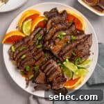 A close up of a platter with braised chuck roast sliced thin garnished with orange and lime.
