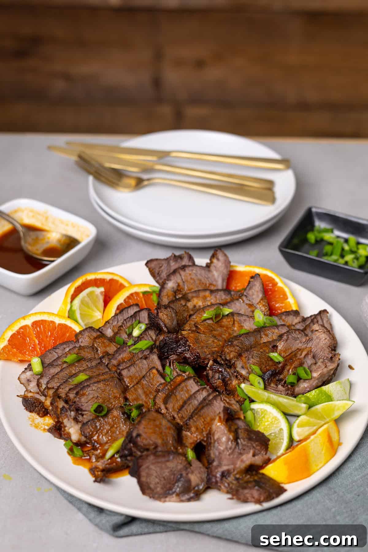 Citrus Soy Braised Chuck Roast Recipe 10 A platter of braised chuck roast with citrus on a grey table.