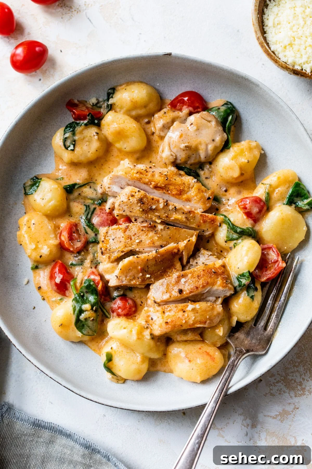 Creamy Chicken Gnocchi Skillet Recipe 2 a bowl of gnocchi coated in a creamy sauce with tomatoes, spinach and sliced chicken