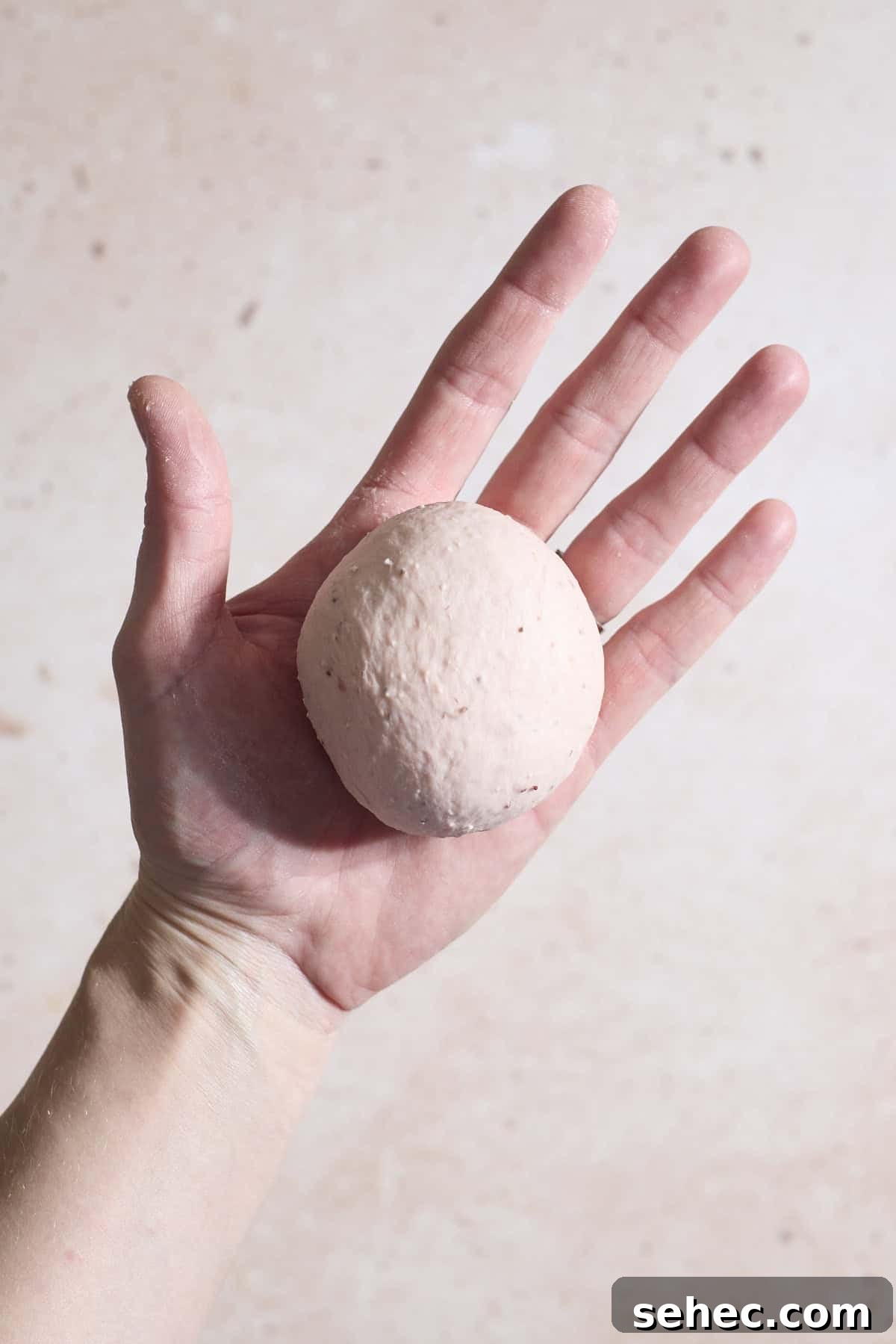 Strawberry Sourdough Discard Bagels 8 Dough shaped into a ball in the palm of a hand.