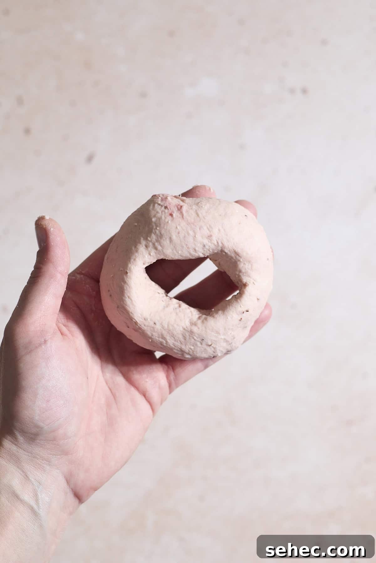 Strawberry Sourdough Discard Bagels 10 A bagel shaped in the palm of a hand.