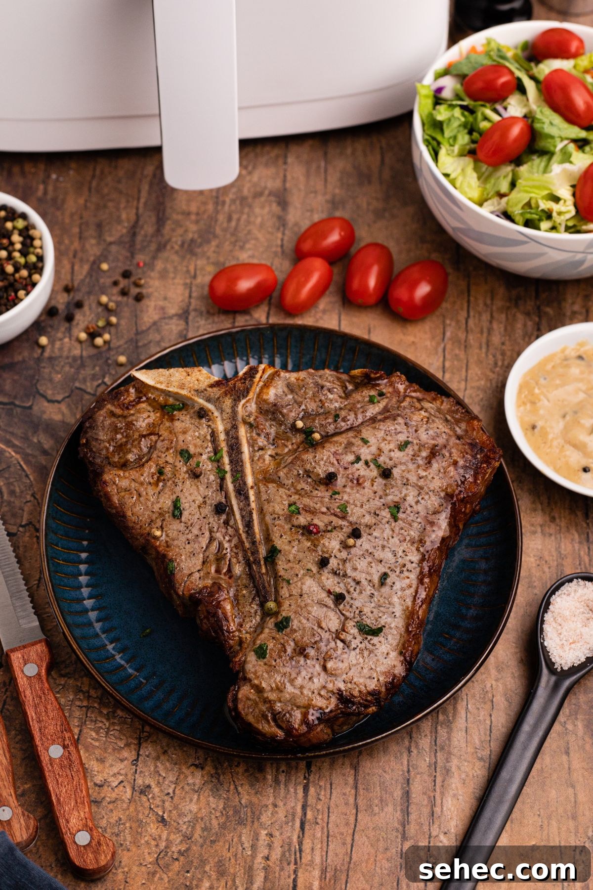 How to Reheat Steak in the Air Fryer 16 t bone steak made in the air fryer on a plate with tomatoes on the table.