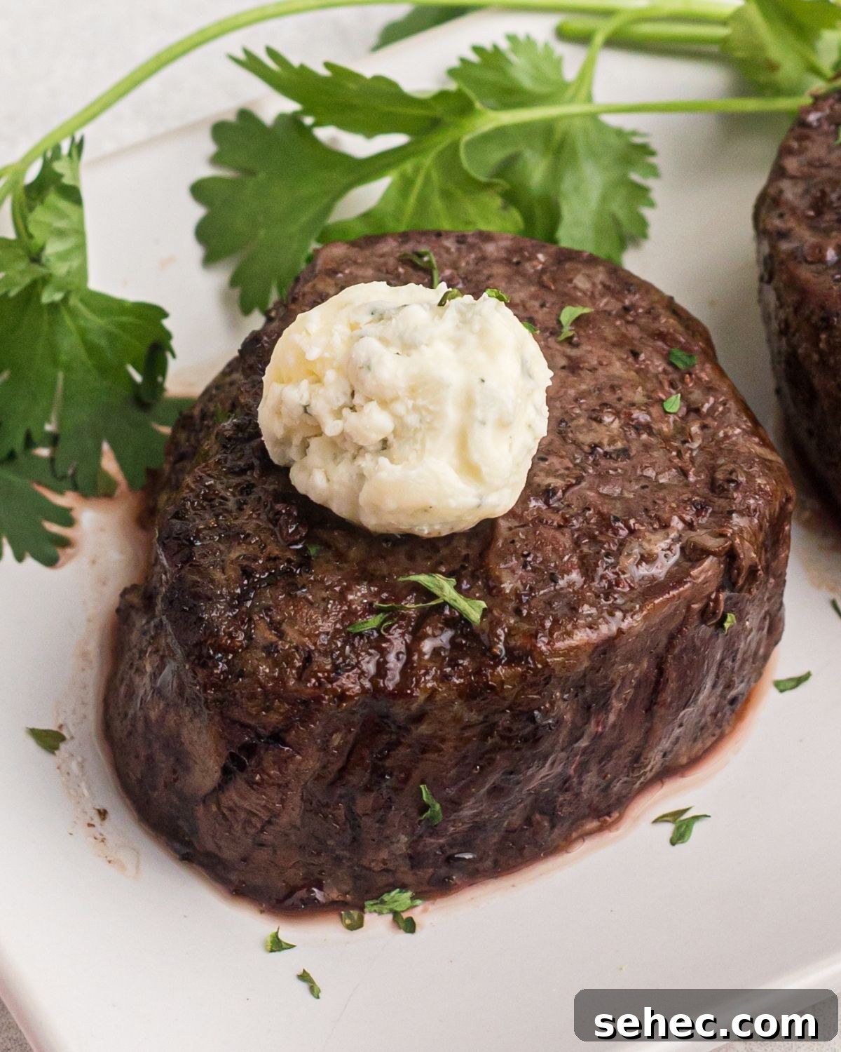 How to Reheat Steak in the Air Fryer 4 filet mignon on a plate with parsley on the side.