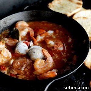 cast iron pot of grilled cioppino with toasted bread