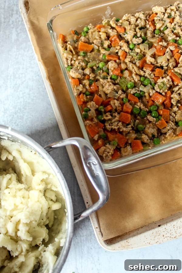 Ground Turkey Shepherds Pie Recipe 4 Delicious ground turkey shepherds pie filling in a dish next to mashed potatoes.