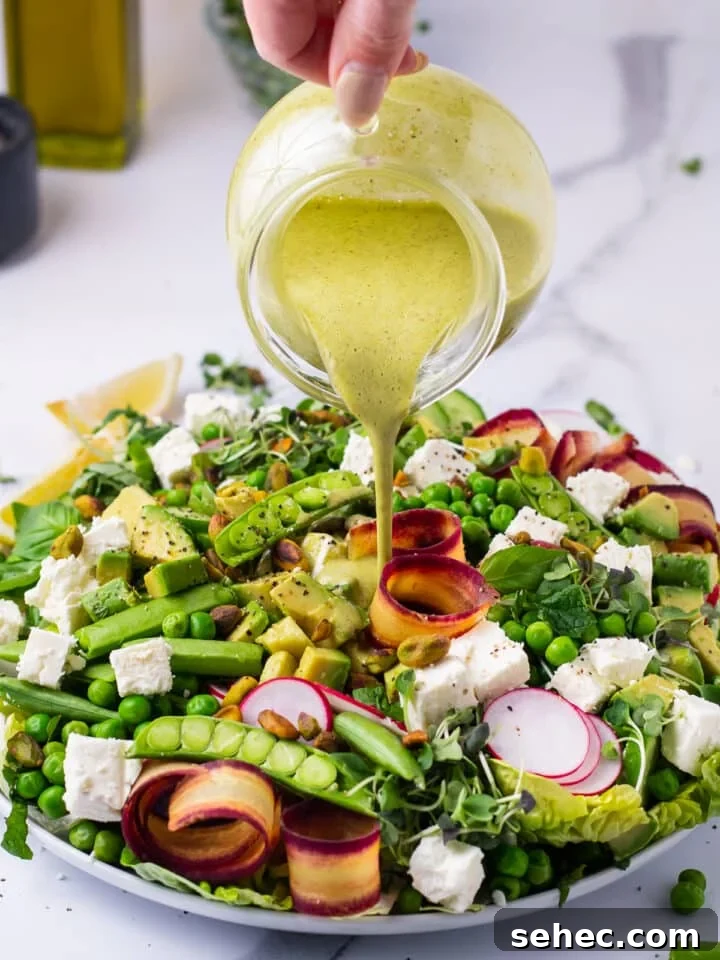 Spring Pea Salad with Lemon Mint Vinaigrette 9 hand pouring a small pitcher of mint dressing on salad