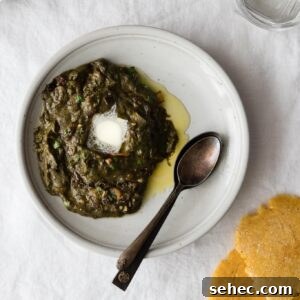Sarson Ka Saag Recipe Stovetop and Instant Pot 16 Sarson Ka Saag with a dollop of butter on a plate with spoons and makai ki roti on the side
