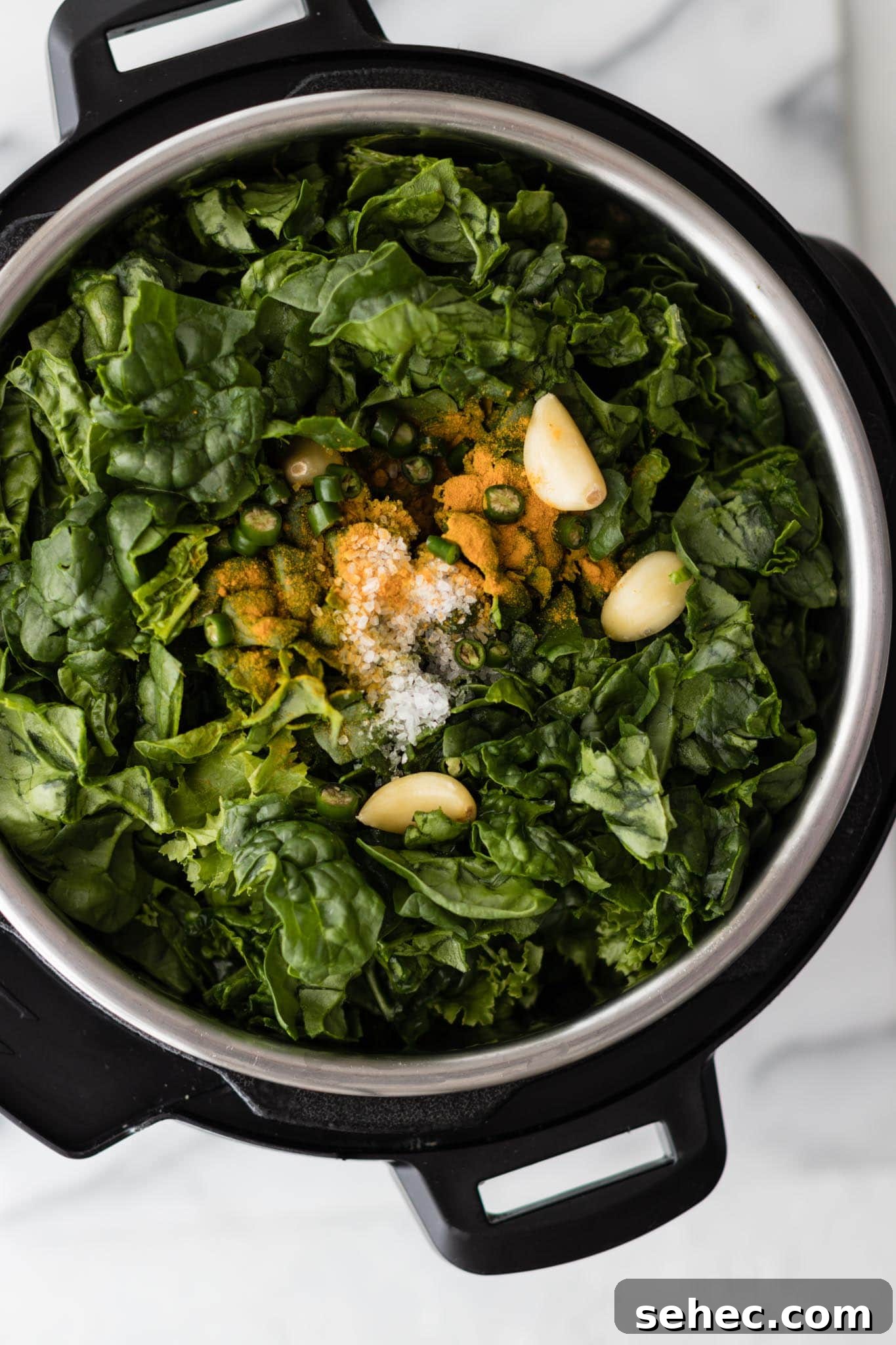 Sarson Ka Saag Recipe Stovetop and Instant Pot 6 Instant Pot filled with mustard greens and spinach, garlic, green chili pepper and turmeric ready to be cooked to make Sarson Ka Saag