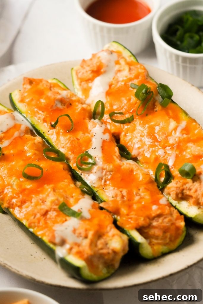 Buffalo Chicken Zucchini Boats Recipe 2 buffalo chicken zucchini boats with ranch dressing and green onions on a plate