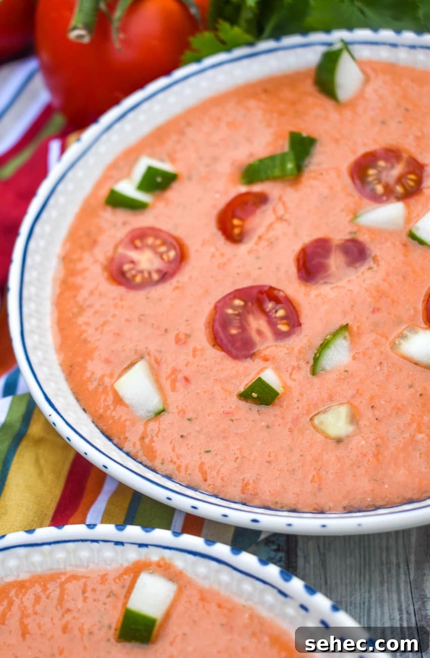 Homemade Gazpacho Recipe with Fresh Tomatoes 3 homemade gazpacho topped with diced cucumber and tomato in two white bowls
