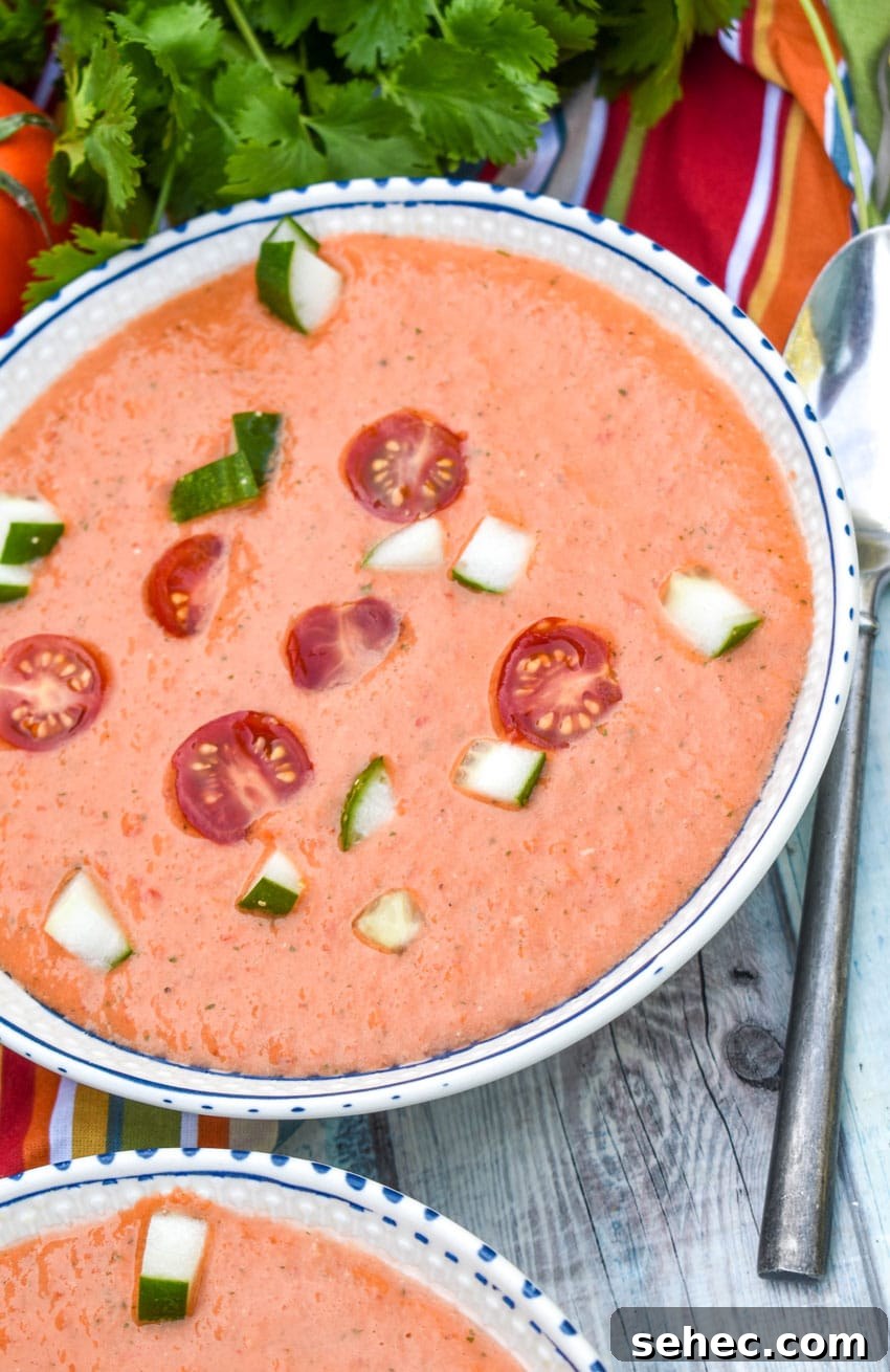 Homemade Gazpacho Recipe with Fresh Tomatoes 5 homemade gazpacho topped with diced cucumber and tomato in two white bowls