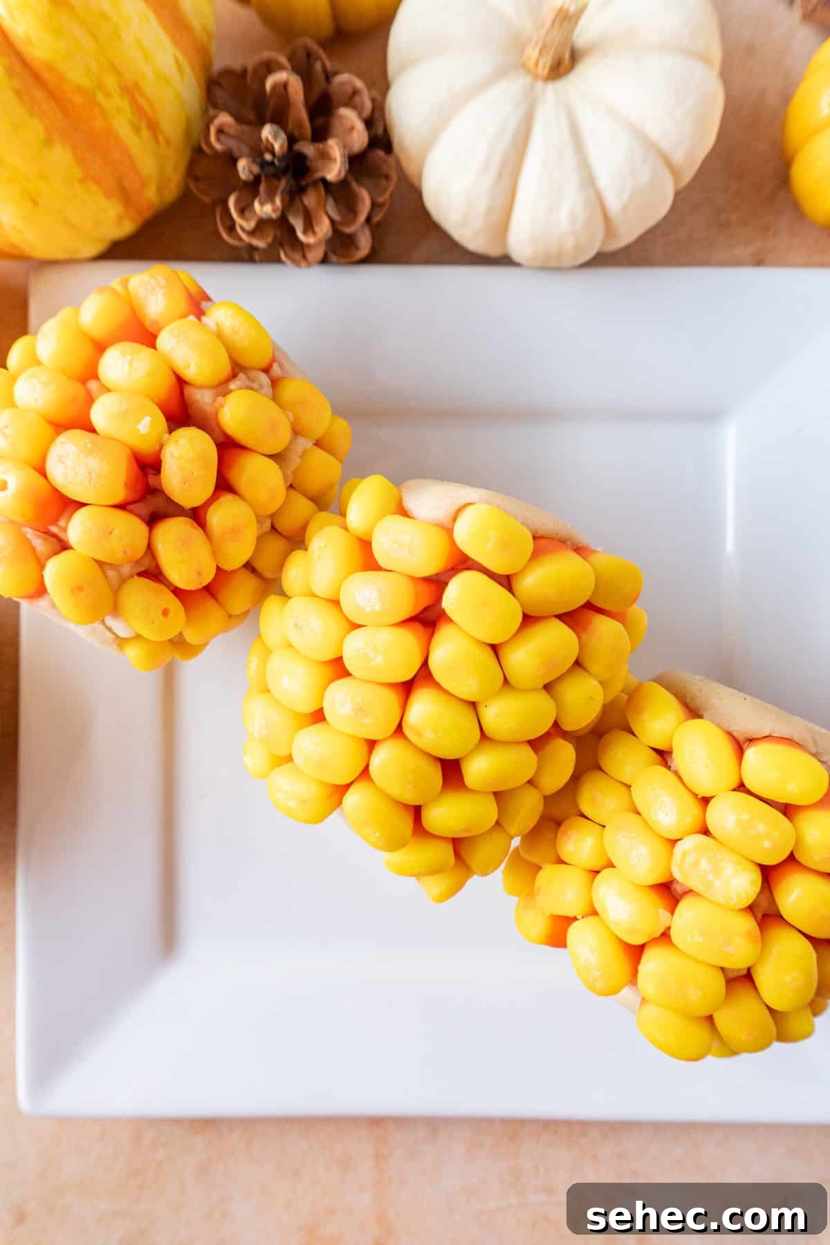 Candy Corn on the Cob Halloween Treats 3 3 candy corn on the cobs on a white square plate.