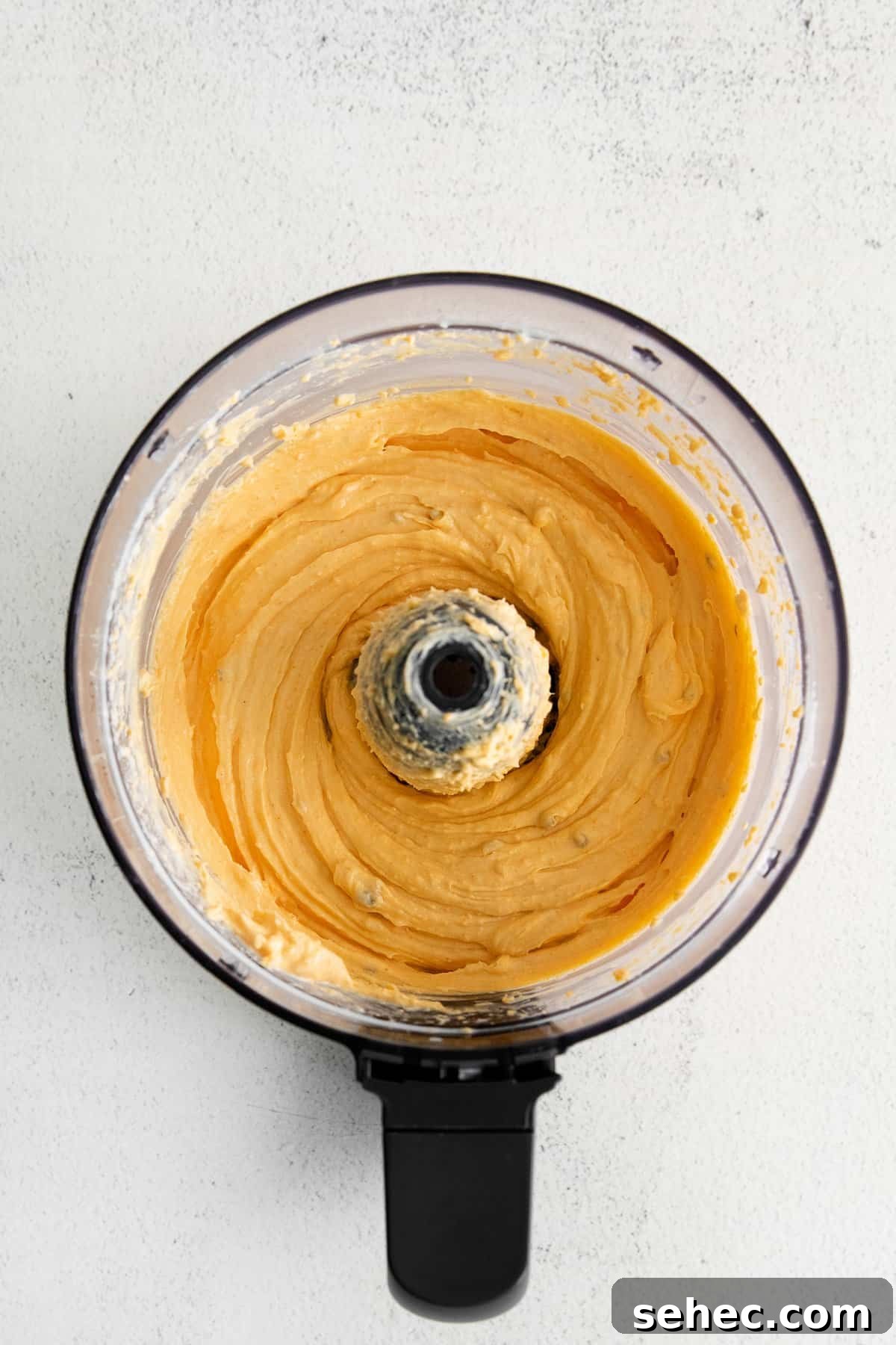 Blended homemade cheese spread. Homemade cheese spread in a food processor.