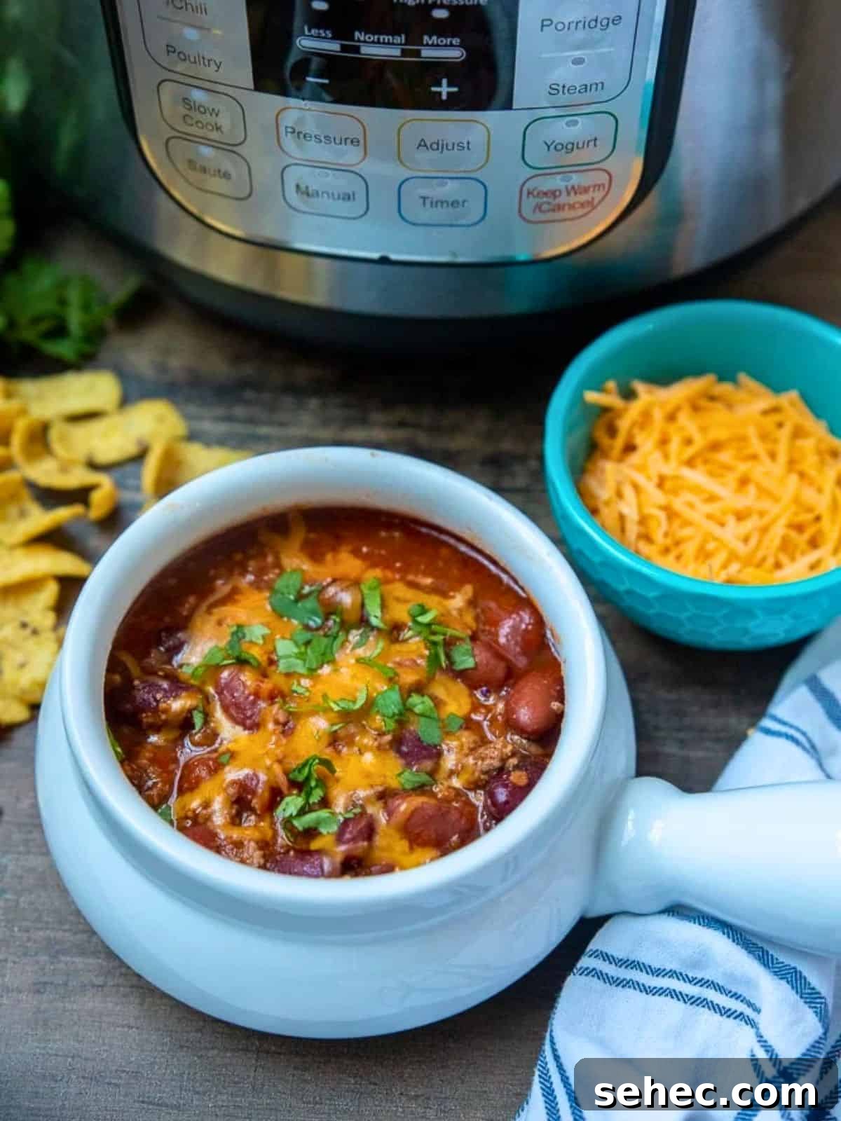 Instant Pot Chili Instant Pot Classic Beef Chili in white bowl next to Instant Pot with corn chips and cilantro on the side.