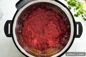 Instant Pot Chili Recipe 5 Instant Pot with beef and bean, beef broth, and crushed tomatoes layered on top.