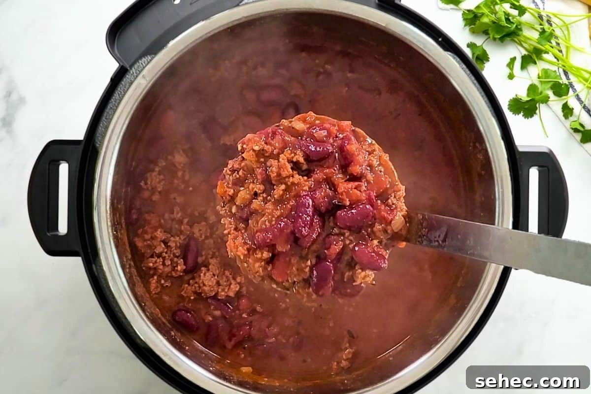 Instant Pot Chili Recipe Scoop of Beef and Bean Instant Pot Chili being ladled out of Instant Pot.
