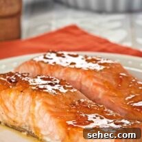 Bourbon Orange Marmalade Glazed Salmon Recipe 4 Orange marmalade and bourbon glazed salmon fillets coated in a glossy citrus glaze on a white plate.