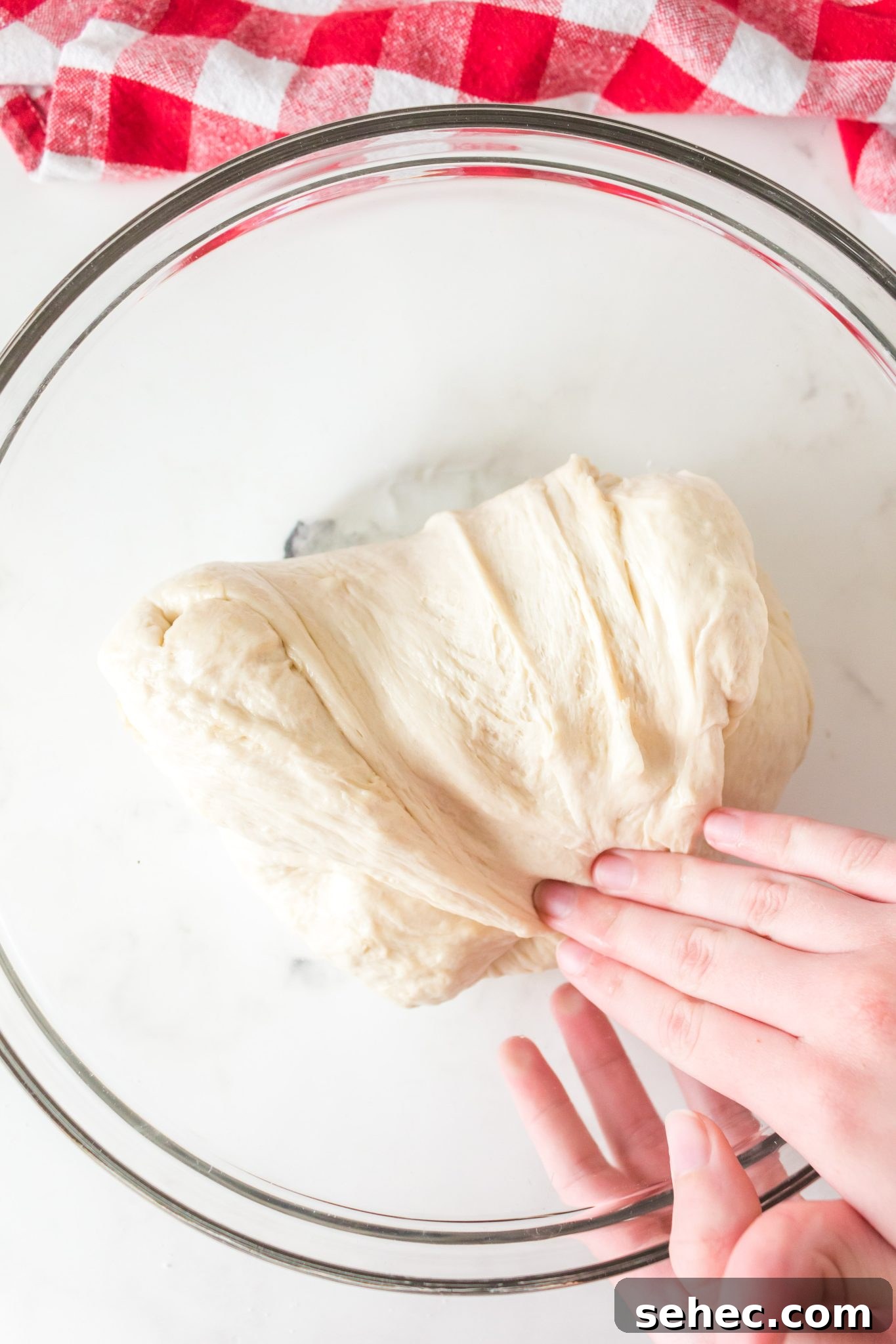 Crispy Chewy Sourdough Pizza Crust Recipe 11 A hand folding homemade sourdough pizza dough over itself