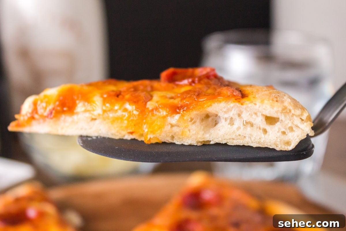 Crispy Chewy Sourdough Pizza Crust Recipe 16 A slice of sourdough pizza sitting on a spatula