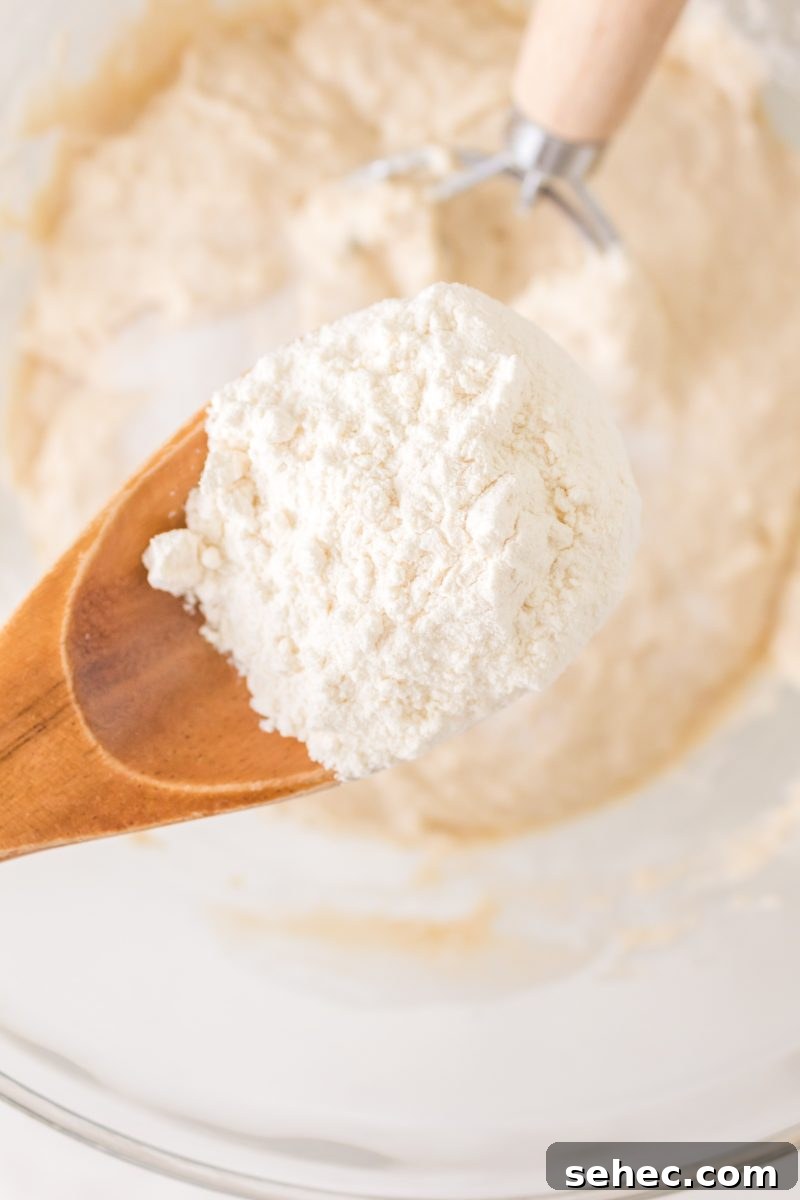 Crispy Chewy Sourdough Pizza Crust Recipe 8 A wooden spoon holding flour over a mixing bowl