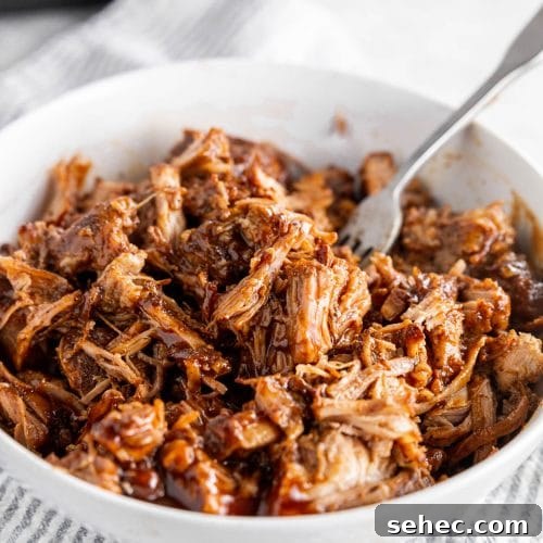 Instant Pot BBQ Pulled Pork Recipe 7 A photo of a large bowl with shredded BBQ pulled pork and a fork.