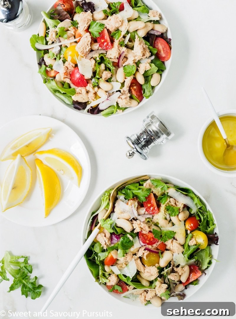 Mediterranean White Bean and Tuna Salad 2 Two bowls of white bean and tuna salad with lemon and olive oil dressing served on the side.
