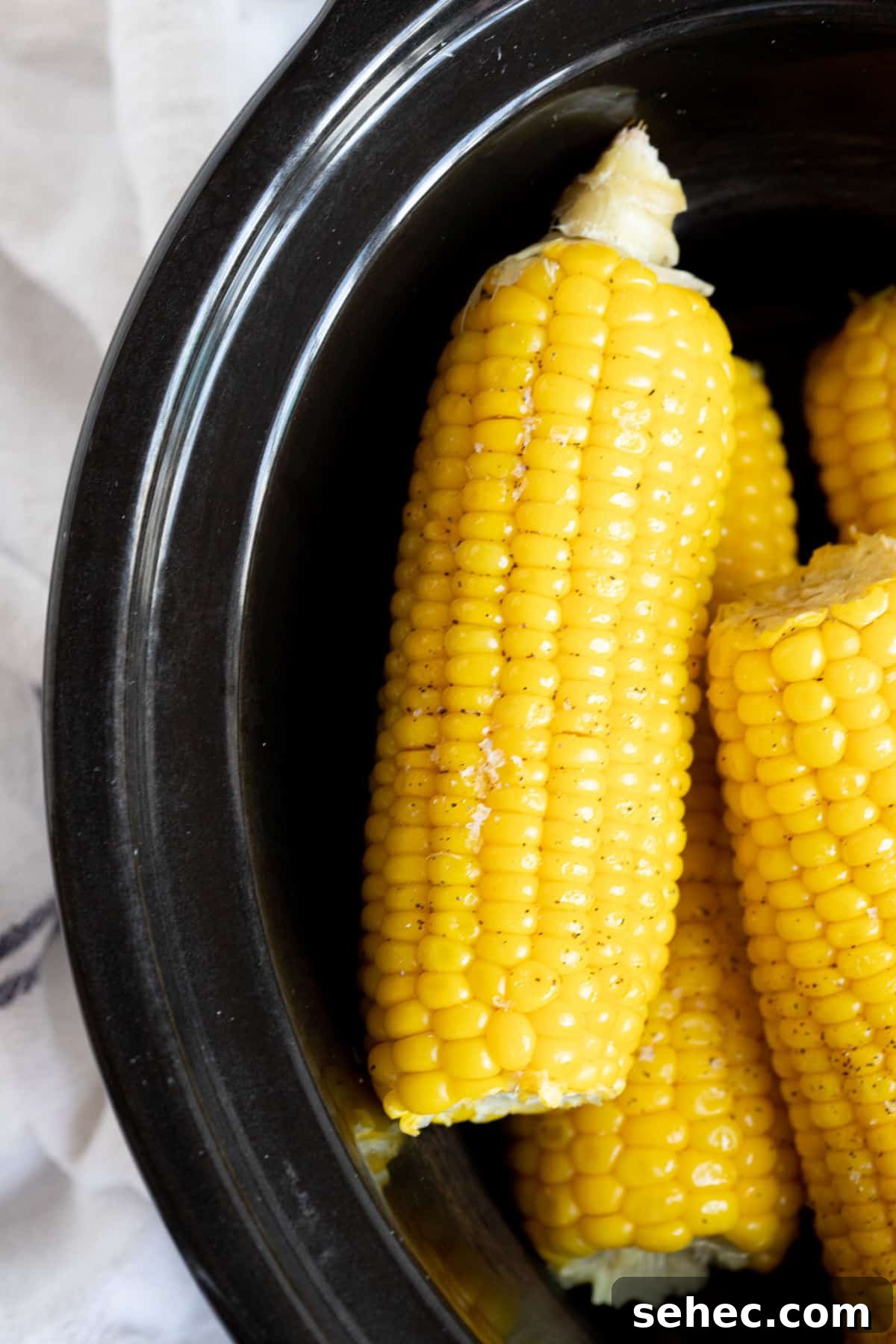 Corn in a black slow cooker.