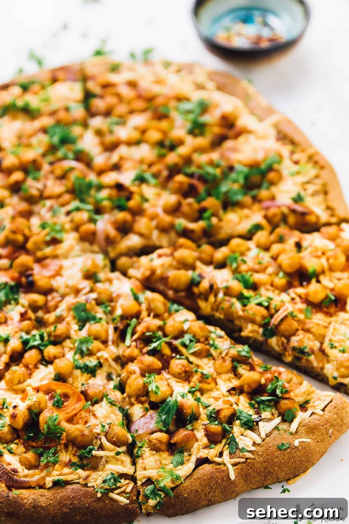 Spicy BBQ chickpea pizza is like a vegan version of BBQ chicken pizza, with a bit of a kick. An easy plant-based dinner ready in a flash! Sliced BBQ chickpea pizza on parchment-lined countertop