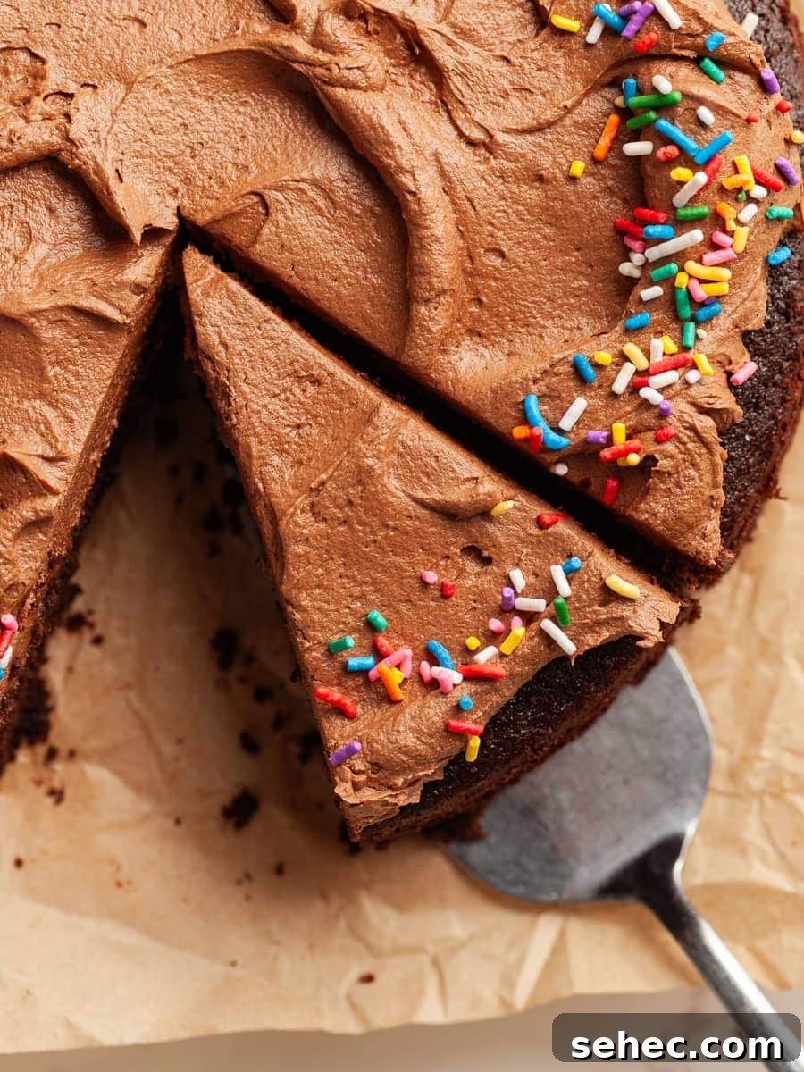 gluten free sourdough chocolate cake with a chocolate frosting and topped with sprinkles on parchment paper