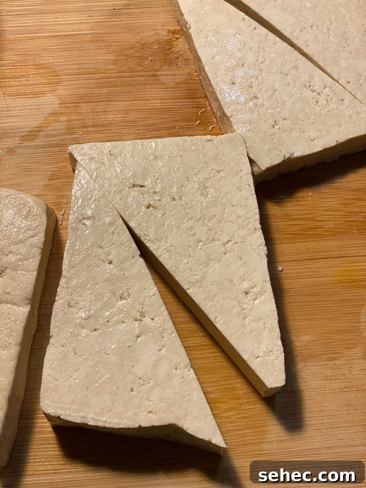 Lemon Basil Tofu Recipe with Crispy Edges 4 process of showing triangular cut of tofu on cutting block